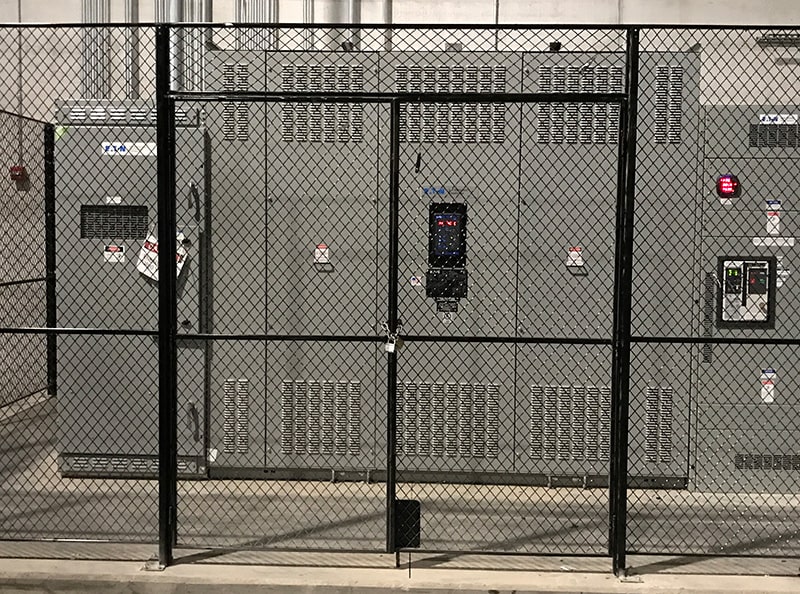 Image of a black Ford Logan double-door utility cage protecting electrical equipment.